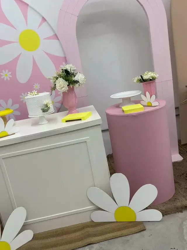 Decoração com painéis em arco rosa, margaridas e cilindros