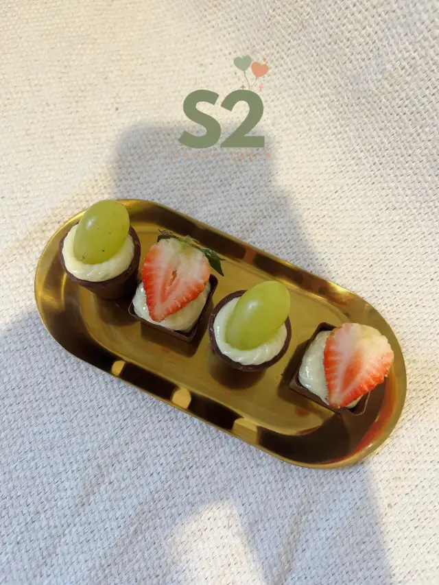 Doces finos com morango e uva em bandeja dourada