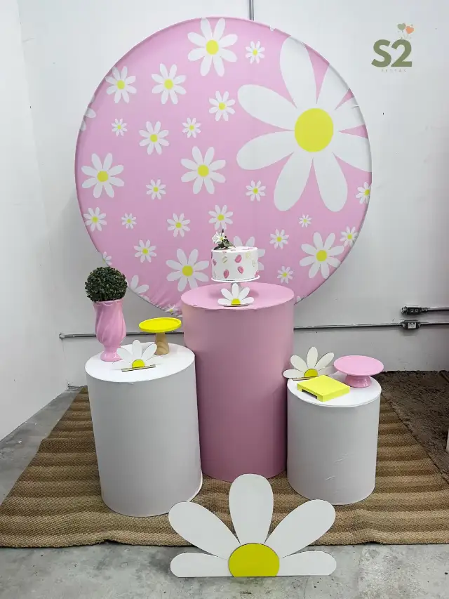 Decoração com painel redondo de margaridas e cilindros rosa e branco